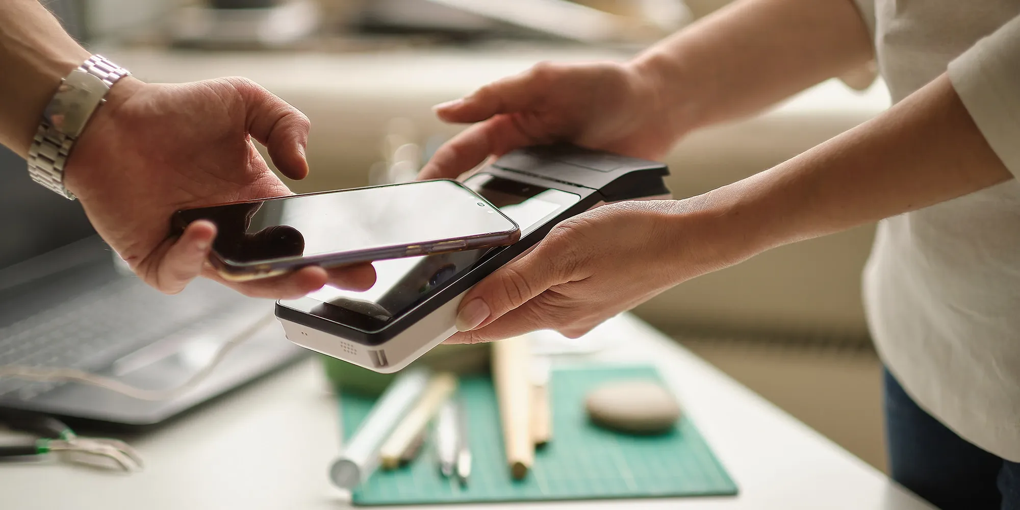 Person using a mobile digital wallet for a contactless NFC payment on a portable POS terminal at a small business.