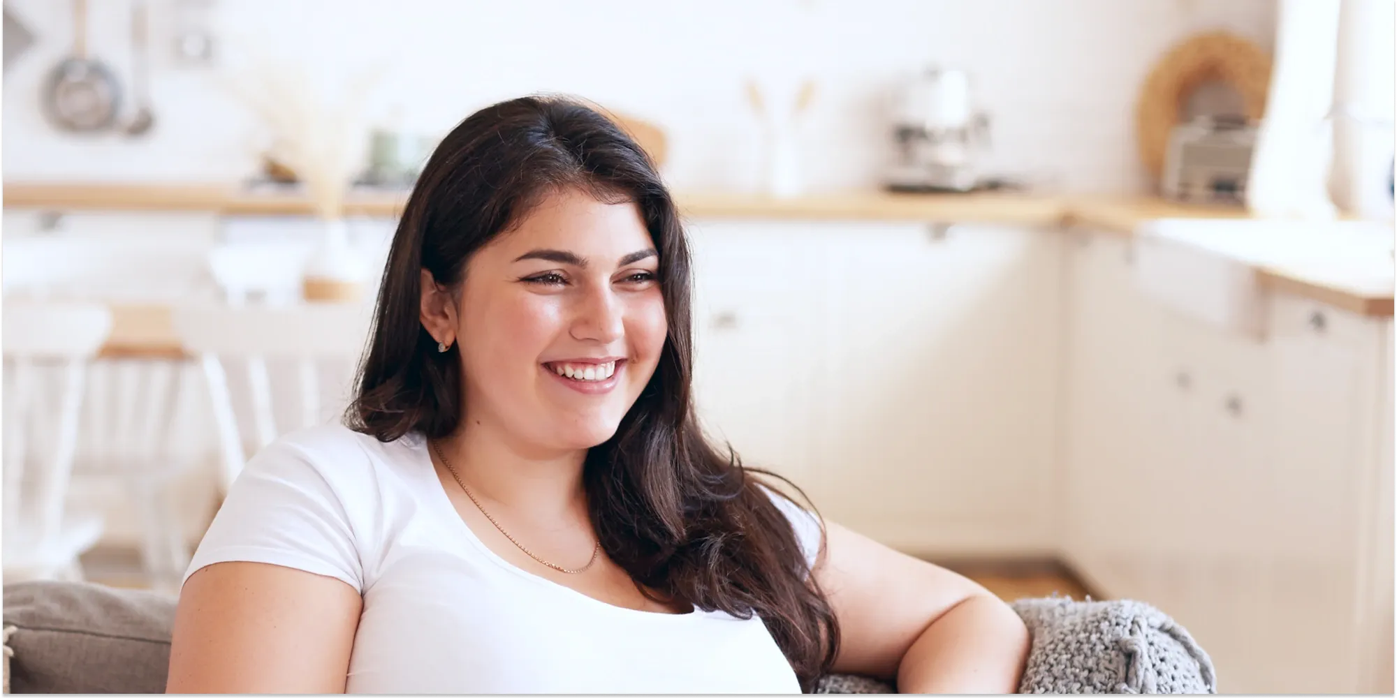 Happy woman in a bright modern kitchen representing healthy lifestyle and wellness at home.