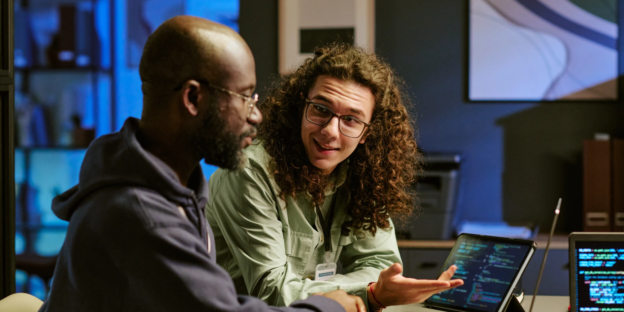 Two developers in an ai-fluent team collaborating and critically evaluating code on a laptop